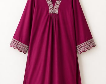 May include: A magenta tunic and matching trousers set. The tunic features long sleeves, a V-neckline, and side slits. The neckline and sleeve cuffs are decorated with white floral embroidery and a scalloped edge. The set is displayed on a hanger.