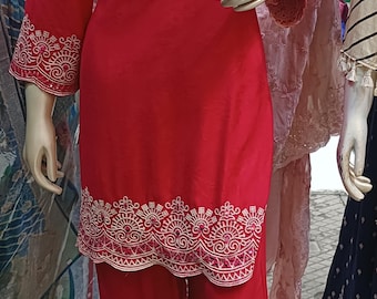 May include: A vibrant red tunic and matching wide-leg trousers set. The tunic features a V-neckline and three-quarter length sleeves, both adorned with intricate white embroidery. The hem of the tunic and the trousers also feature matching embroidery.