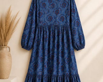 May include: A long-sleeved midi dress in a deep blue hue, featuring a repeating intricate floral pattern in shades of red and light blue. The garment has a round neckline, a gathered waistline, and a tiered skirt with a ruffled hemline.