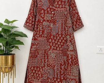 May include: A knee-length, rust-red tunic featuring a multi-patterned print with paisley and geometric motifs, a V-neckline, and three-quarter sleeves, paired with matching rust-red wide-leg trousers decorated with a white polka dot pattern.