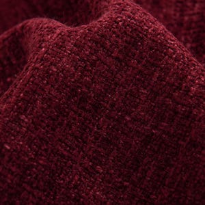 May include: Close-up of a textured fabric in a deep burgundy colour. The material has a woven appearance with a slightly uneven surface, creating a rich, tactile look. The folds and shadows add depth to the image, highlighting the fabric's texture.
