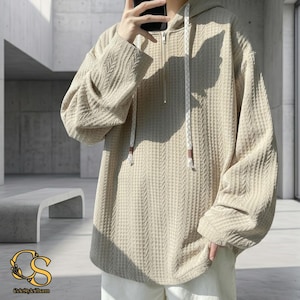 May include: Beige waffle-knit hoodie with a half-zip and drawstring hood. The long-sleeved top has a textured pattern and a relaxed fit. The hoodie is a neutral colour and suitable for casual wear.