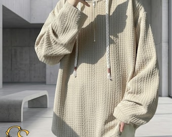 Puede incluir: Sudadera con capucha de punto gofrado beige con cierre de media cremallera y capucha con cordón. La parte superior de manga larga tiene un patrón texturizado y un ajuste relajado. La sudadera es de color neutro.
