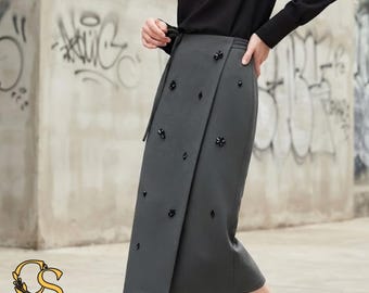 Puede incluir: Una falda midi gris carbón con un diseño de panel frontal superpuesto y adornos florales negros dispersos. La falda se combina con una blusa negra de manga larga. El logotipo de CeleStyleCharm es visible en la esquina inferior izquierda.