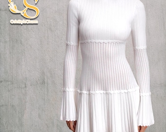 Puede incluir: Vestido blanco de manga larga con cuello alto. El vestido presenta un corpiño de punto acanalado y una falda acampanada con dobladillo festoneado. Las mangas tienen puños acampanados. El logo de la marca "CuteStyleCharm" está en la esquina superior izquierda.