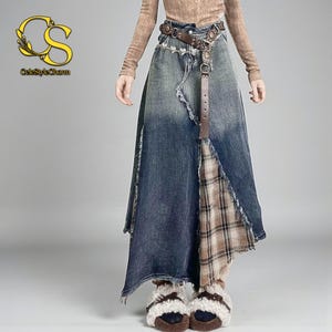 Può includere: Una gonna di jeans dal design unico. La gonna presenta un lavaggio blu sbiadito, una cintura in pelle marrone e un pannello a quadri. La gonna ha un orlo asimmetrico e un aspetto invecchiato. Il logo "CeleStyleCharm" è visibile in alto a sinistra.