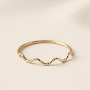 May include: A thin, gold-toned metal ring featuring a continuous, smooth, wavy or serpentine design that circles the entire band. The ring has a polished, reflective surface and a uniform thickness throughout its delicate, curved structure.