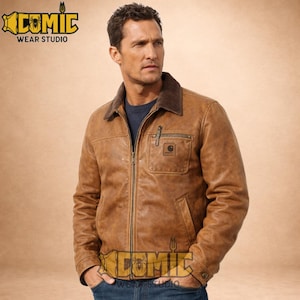 May include: A brown leather jacket with a corduroy collar and a front zipper. The jacket has a Carhartt logo patch on the chest pocket. The jacket is worn over a dark blue shirt. The image includes the text "COMIC WEAR STUDIO".