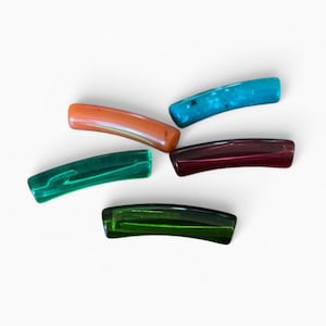 Può includere: Cinque fermagli per capelli curvi in colori assortiti, tra cui arancione, blu brillante, rosso scuro, verde smeraldo e verde bosco. Ogni accessorio per capelli presenta una finitura liscia e lucida con una forma leggermente arcuata.
