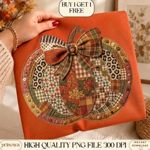 Puede incluir: Una superficie de tela naranja con una gran aplicación central de calabaza hecha de varios parches estampados, incluyendo estampado de leopardo, cuadros y hojas de otoño. Un lazo de tela corona la calabaza y el borde está adornado con pequeños botones.