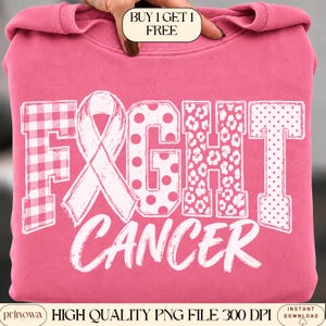 Op de afbeelding: Een felroze sweatshirt met de tekst FIGHT CANCER in het wit. De letter I is vervangen door een roze bewustzijnslintje. De letters F, G, H en T bevatten witte patronen zoals vichy-ruitjes, stippen en een luipaardprint.