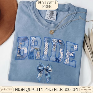 May include: A light blue Comfort Colors t-shirt with the word "BRIDE" appliqued in patchwork fabric. The letters are outlined in blue and feature floral and patterned designs. A matching bow is below the word. A silver necklace with a pendant is on the shirt.