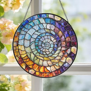 Puede incluir: Una ventana redonda de vidrieras colgante con un diseño en espiral. La ventana presenta un mosaico de piezas de vidrio de colores en tonos de azul, verde, amarillo, naranja y morado. Está enmarcada en negro y suspendida por una cadena.