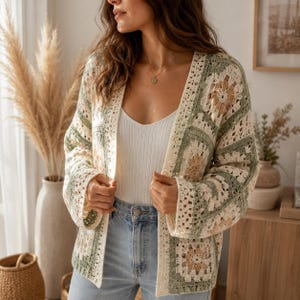 May include: A crochet cardigan featuring a granny square pattern in shades of sage green, cream, and tan. The open-front garment has long sleeves and a textured, hand-stitched appearance, worn over a white ribbed tank top and light blue denim jeans.