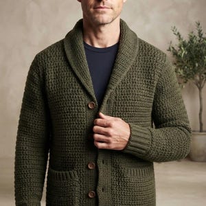 Könnte beinhalten: Eine olivgrüne Langarm-Strickjacke mit strukturiertem Strickmuster, breitem Schalkragen und vier braunen Knöpfen auf der Vorderseite. Das Kleidungsstück verfügt über zwei Vordertaschen und gerippte Bündchen und wird über einem dunkelblauen T-Shirt getragen.