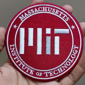 May include: A round, red embroidered patch featuring the text "MASSACHUSETTS INSTITUTE OF TECHNOLOGY" in white lettering. The center displays "MIT" in white and gray block letters, with a white border and star accents.
