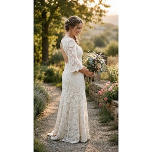 May include: A floor-length off-white crochet dress featuring an open back, three-quarter length sleeves, and intricate floral lace patterns throughout the fabric. The garment is fitted through the bodice and flares slightly toward the hem.