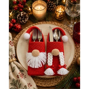 Peut inclure: Deux porte-couverts en crochet rouge en forme de gnomes avec des pompons blancs sur leurs bonnets. L'un possède une barbe en laine blanche et contient une fourchette, l'autre a deux tresses blanches avec des nœuds rouges et contient un couteau et une cuillère.
