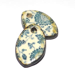 Könnte beinhalten: Zwei ovale Anhänger aus Keramik mit einem blauen und weißen Blumenmuster. Die Anhänger haben oben ein Loch zum Aufhängen.