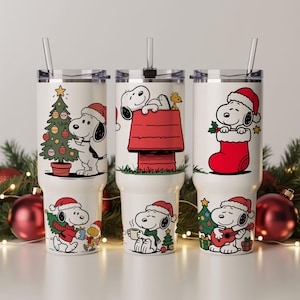 May include: Three white insulated tumblers featuring Snoopy in Christmas scenes. Each tumbler has a different design, including Snoopy decorating a tree, on his doghouse, and with a stocking. Each tumbler has a black lid and a clear straw.