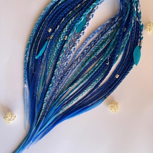 Può includere: Dreadlocks sintetici blu e verde acqua con accenti bianchi e piume decorative. I dread sono disposti in un motivo fluido, con varie sfumature di blu. Sono incluse anche piccole perline e ciondoli argentati.