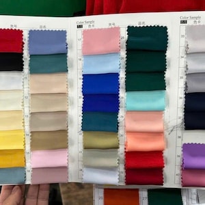 May include: A fabric colour sample chart featuring a grid of rectangular textile swatches in various colours including red, black, white, yellow, blue, green, pink, and purple, organised in numbered rows with headers labelled Color Sample.