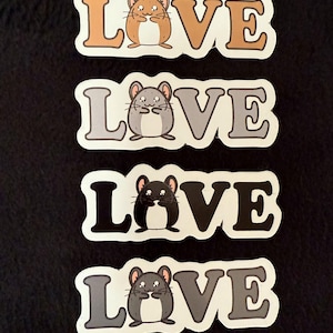 May include: Four stickers with the word "LOVE" in a bold font, each featuring a different colored hamster illustration. The hamsters are in shades of brown, gray, and black, with white outlines. The stickers are on a black background.