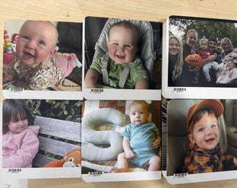 May include: A collection of six photographs featuring babies and young children. The images showcase various settings, including a high chair, outdoor scenes, and family portraits. Each photo is printed on a rectangular card with a barcode at the bottom.