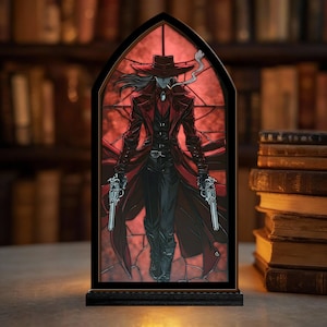 May include: A stained glass-style light-up panel featuring a figure in a long red coat, hat, and holding two pistols. The background is red, and the frame is black. The figure is smoking a cigarette. The base is black.
