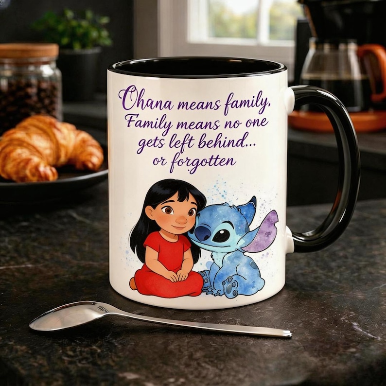 Op de afbeelding: Witte keramische mok met een zwarte binnenkant en handvat. De mok heeft een afbeelding van Lilo en Stitch, met de tekst "Ohana betekent familie. Familie betekent dat niemand achterblijft... of vergeten wordt."