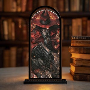 May include: A framed, illuminated artwork featuring a character in a red coat and hat, holding a gun. The image has a gothic theme, with a dark background and a black base. The artwork is displayed in front of a bookshelf.