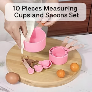 May include: A pink measuring cup is being filled with a white liquid. The image shows a set of pink measuring cups and spoons with wooden handles. The text on the image says "10 Pieces Measuring Cups and Spoons Set".