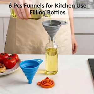 May include: A clear glass bottle being filled with oil using a gray silicone funnel. The image shows three funnels in different colors: gray, blue, and orange. The text at the top reads "6 Pcs Funnels for Kitchen Use Filling Bottles."