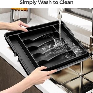 Puede incluir: Una bandeja de cubiertos de pl&aacute;stico negro con m&uacute;ltiples compartimentos se lava bajo un grifo. La bandeja es rectangular y est&aacute; dise&ntilde;ada para organizar la cuberter&iacute;a. El texto "Simply Wash to Clean" es visible en la parte superior de la imagen.