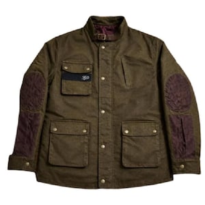 May include: An olive green jacket featuring a stand-up collar with a buckle strap, a front button closure, and four front pockets. The sleeves include dark purple quilted elbow patches and matching lower sleeve panels, with a small logo on the chest.