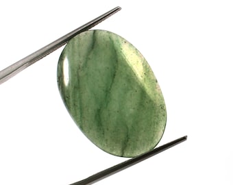 May include: A polished, oval-shaped green gemstone with darker green veining. The stone is held by silver tweezers against a white background. The gemstone has a smooth, reflective surface and is likely used in jewelry or other decorative items.