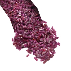 Peut inclure: Un tas de pierres précieuses de rubis brutes, de tailles et de formes variées, s'échappant d'un contenant blanc. Les pierres précieuses sont d'un rouge profond et riche avec des zones plus claires et translucides. Le fond est blanc.