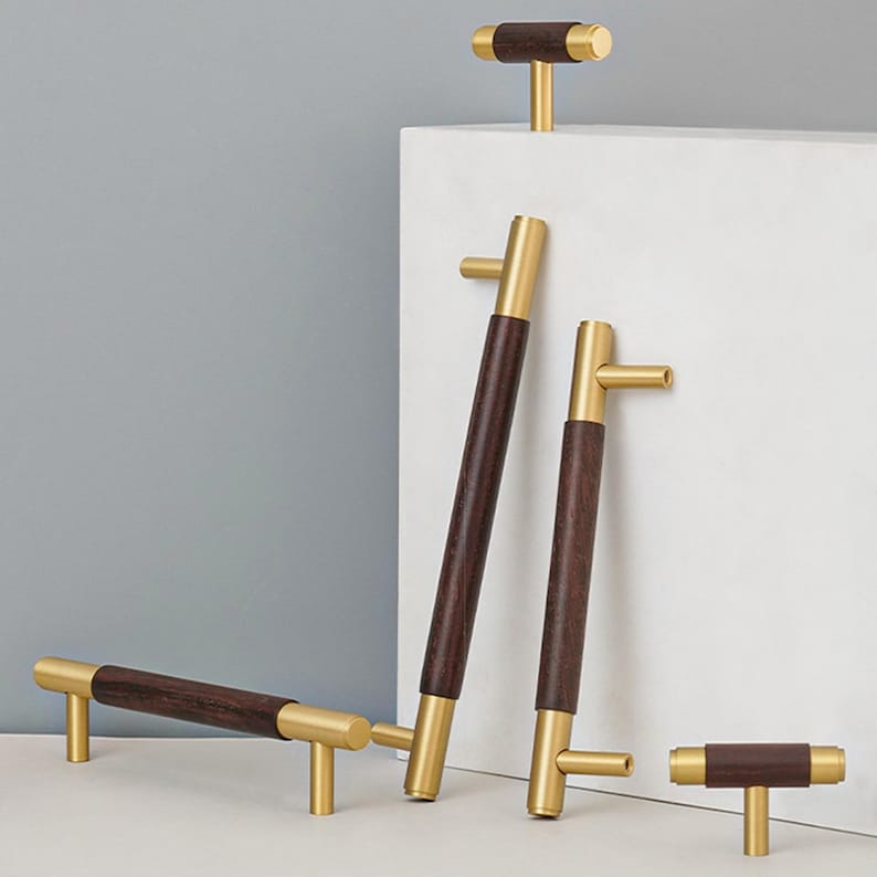 Peut inclure: Ensemble de quincaillerie de meubles moderne, combinant du bois brun fonc&eacute; et du m&eacute;tal dor&eacute; bross&eacute;. L'ensemble comprend des poign&eacute;es et des boutons de diff&eacute;rentes tailles, mettant en valeur un design minimaliste. Les poign&eacute;es et les boutons sont en cm.