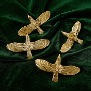 Może przedstawiać: Zestaw trzech ceramicznych kubków z nakrapianym, matowym wykończeniem. Kubki są w odcieniach kremu, jasnoszarym i ciemnoszarym. Każdy kubek ma prosty, minimalistyczny design, idealny do kawy lub herbaty.