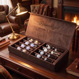May include: A rectangular brown leather storage box with a hinged lid featuring the embossed word Personalized. The interior is divided into eight compartments, each containing a pair of spectacles with various frame styles and lens tints.
