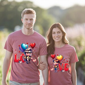 May include: Matching maroon t-shirts with a cartoon design featuring the word "LOVE" in red letters, balloons, and cartoon characters. The shirts are short-sleeved and worn by a man and a woman.