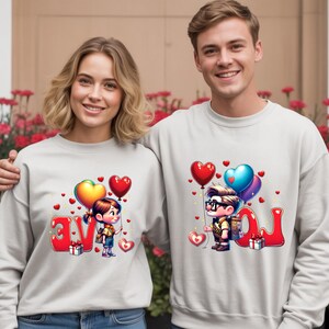 May include: Matching light gray sweatshirts with a cartoon design featuring a boy and girl holding heart-shaped balloons. The word "LOVE" is spelled out in red letters. A gift box is also included in the design.