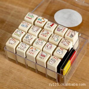 May include: A collection of small, rectangular wooden stamps featuring cat illustrations and Korean text, housed in a clear plastic case. The stamps display various cat designs and words such as "START," "END," "YES," and "NO."
