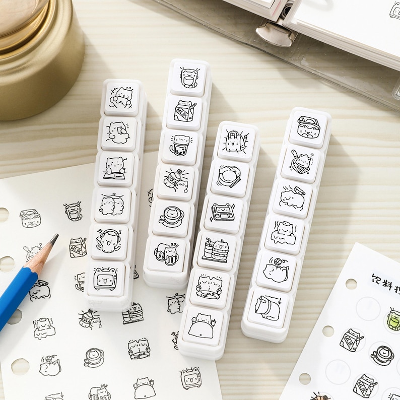 May include: Four white rectangular stamp blocks featuring black line art illustrations of cartoon cats in various activities. Each block contains six individual square stamps with unique designs, including cats with milk, books, headphones, and food items.