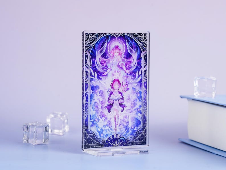 May include: A clear acrylic stand featuring a vibrant illustration of two anime-style figures in shades of purple, blue, and white. The artwork is framed by a decorative border. The stand is on a light blue surface.