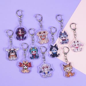 K&ouml;nnte beinhalten: Eine Sammlung von Acryl-Schl&uuml;sselanh&auml;ngern mit Charakterdesigns im Anime-Stil. Jeder Schl&uuml;sselanh&auml;nger hat einen silbernen Metallring und zeigt einen anderen Charakter in verschiedenen Tierkost&uuml;men. Der Hintergrund ist ein Farbverlauf aus Lila und Rosa.