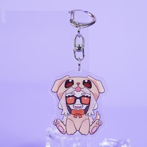 K&ouml;nnte beinhalten: Ein klarer Acryl-Schl&uuml;sselanh&auml;nger mit einer Zeichentrickfigur in einem Hundekost&uuml;m mit Brille und Fliege. Der Schl&uuml;sselanh&auml;nger hat einen silbernen Metallverschluss und -ring. Die Figur ist in den Farbt&ouml;nen Beige, Rot und Schwarz gehalten.