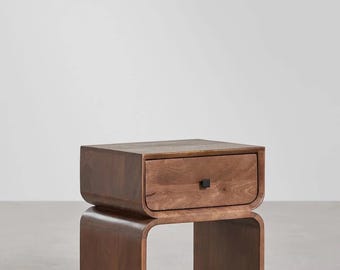 May include: A modern, wooden nightstand with a single drawer and a curved design. The nightstand is made of dark brown wood and features a black square drawer pull. The overall design is minimalist and contemporary.