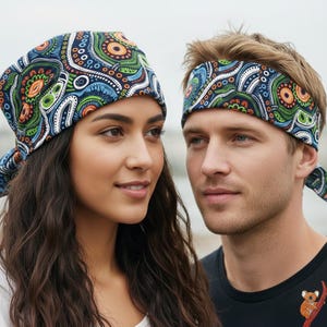 May include: A woman and a man are wearing matching headwear. The headwear features a colourful pattern of blue, green, orange, and white swirls and dots. The woman wears a headscarf, and the man wears a headband.