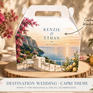 May include: A white gable box featuring a printed coastal scene of a Mediterranean terrace overlooking the sea, with pink bougainvillea and lemons. The text reads KENZIE & ETHAN and 09.16.2027, with an arrow pointing to the text labelled Custom Wordings.